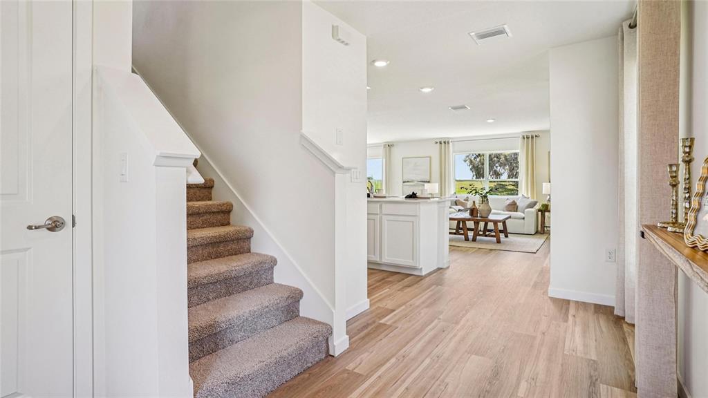 A carpeted staircase leads to an open-concept living area with light wood flooring — 9062 SW 47TH COURT, OCALA, FL