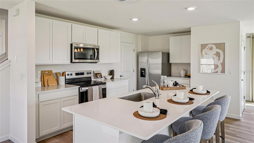 A modern kitchen features white cabinetry, stainless steel appliances, and a large central island — 9062 SW 47TH COURT, OCALA, FL
