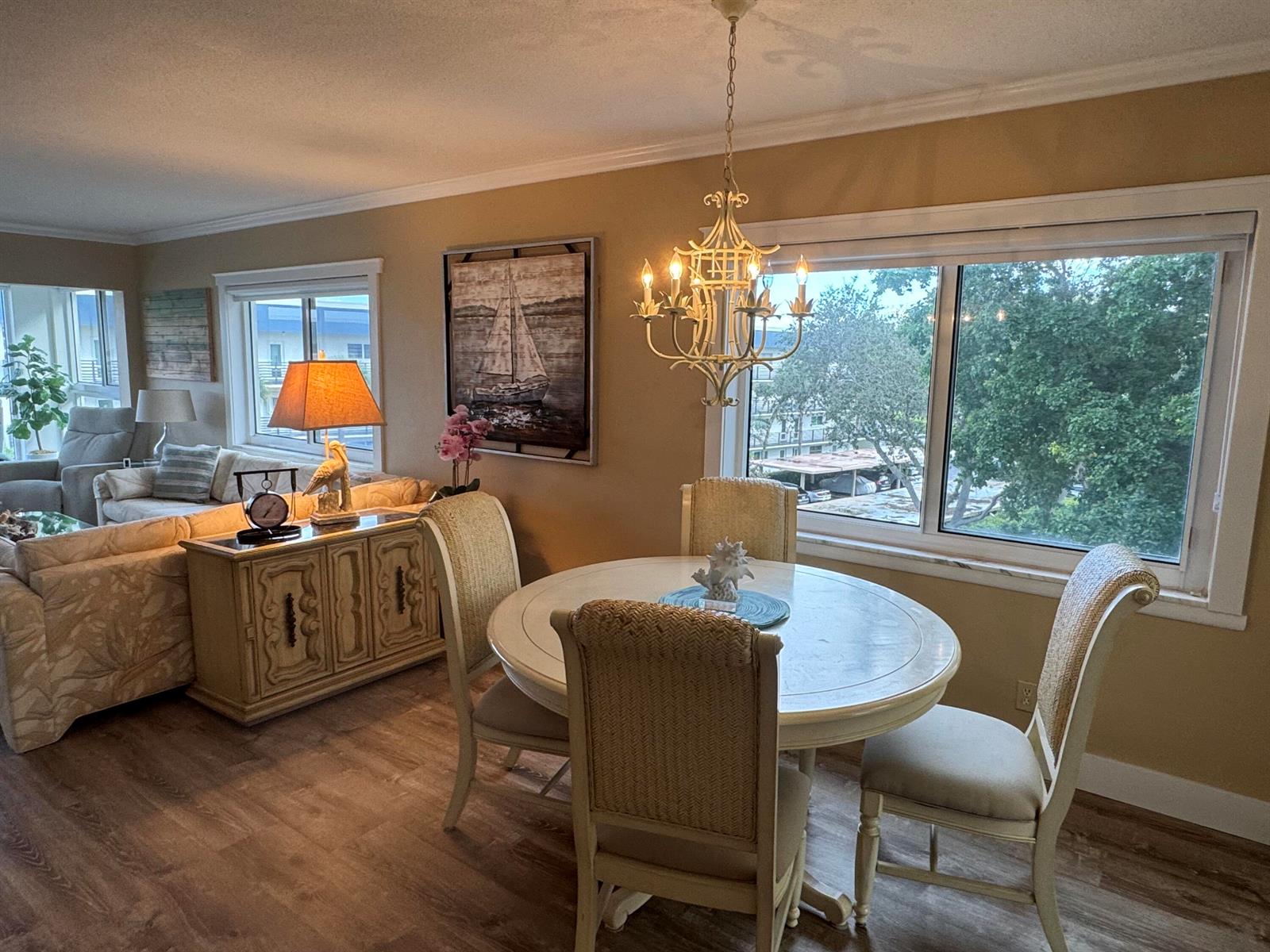 A dining area with a round table and chandelier sits beside a living room space — 3401 Spanish Trail # 455, Delray Beach FL 33483, DELRAY BEACH, FL