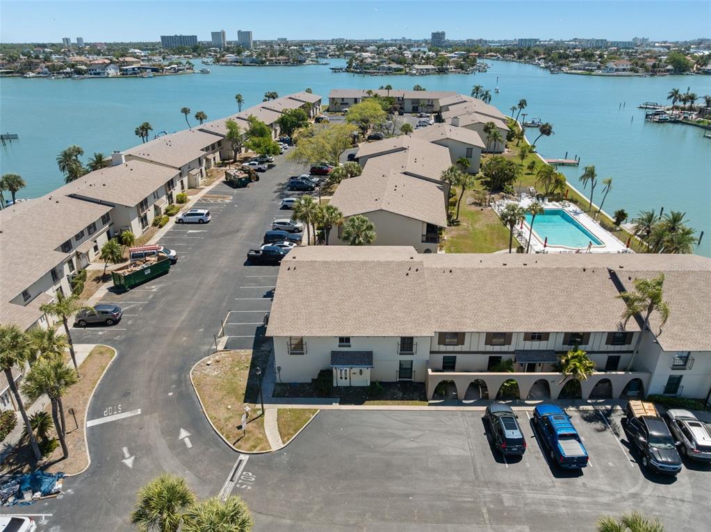 An aerial view shows a multi-unit residential complex with a parking lot and swimming pool — 505 PLAZA SEVILLE COURT UNIT 11, TREASURE ISLAND, FL