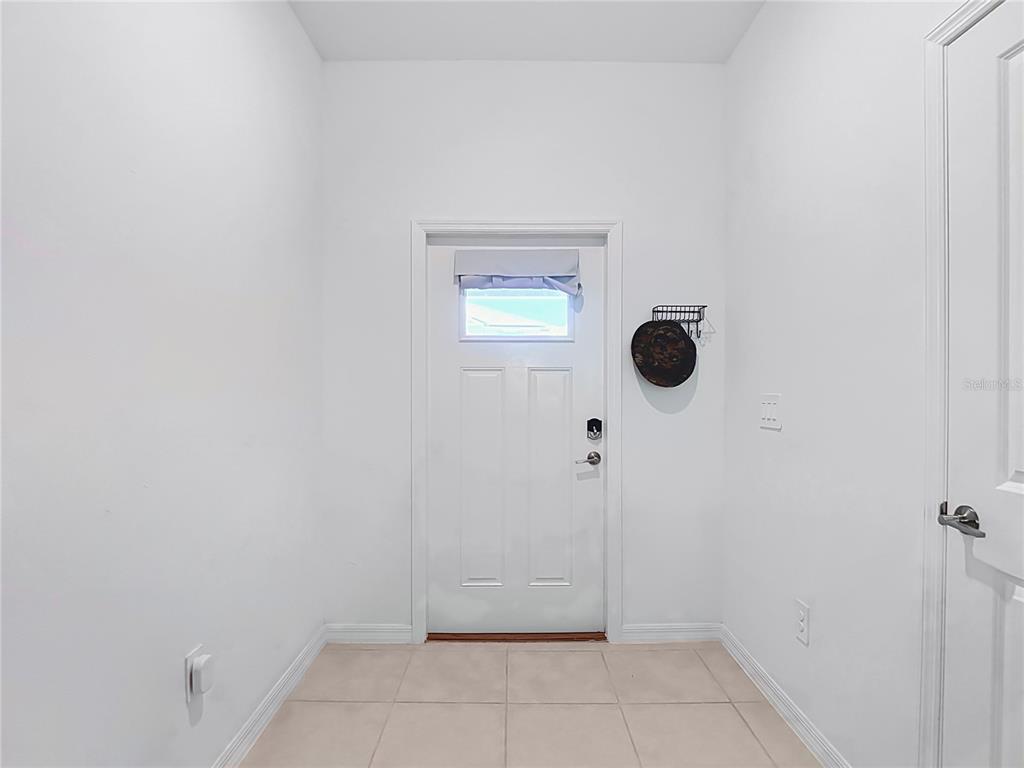 An entryway features a white front door, light-colored tile flooring, and white walls — 32067 SPICEBERRY STREET, SAN ANTONIO, FL