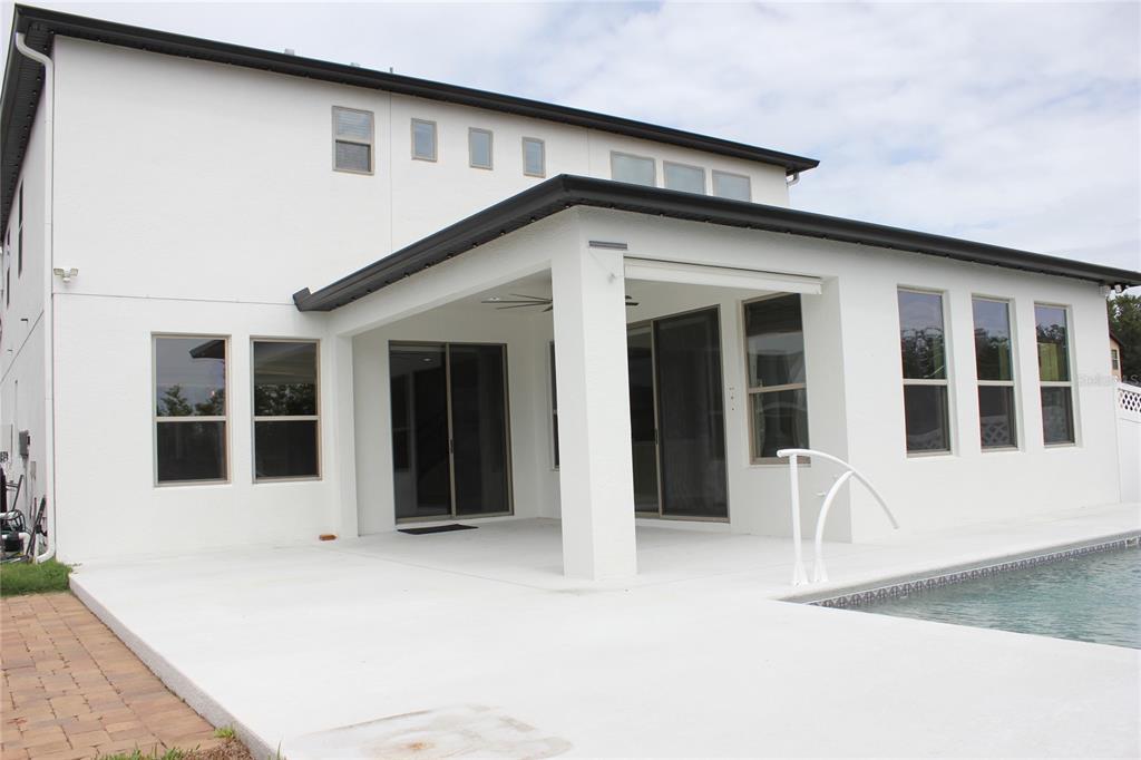 The exterior of a two-story white house features a covered patio and a swimming pool — 4203 CAPLOCK STREET, CLERMONT, FL