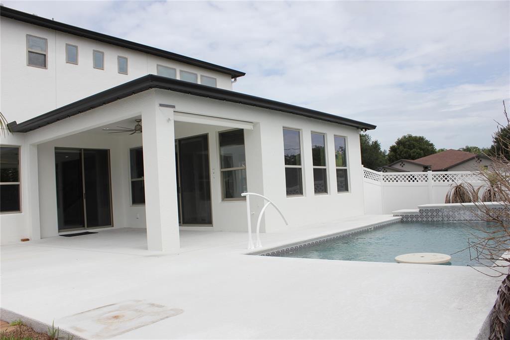A white two-story house exterior features a covered patio, swimming pool, and white fence — 4203 CAPLOCK STREET, CLERMONT, FL