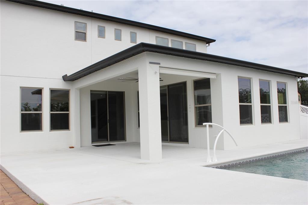 A white two-story house exterior features a covered patio, sliding glass doors, and a pool — 4203 CAPLOCK STREET, CLERMONT, FL