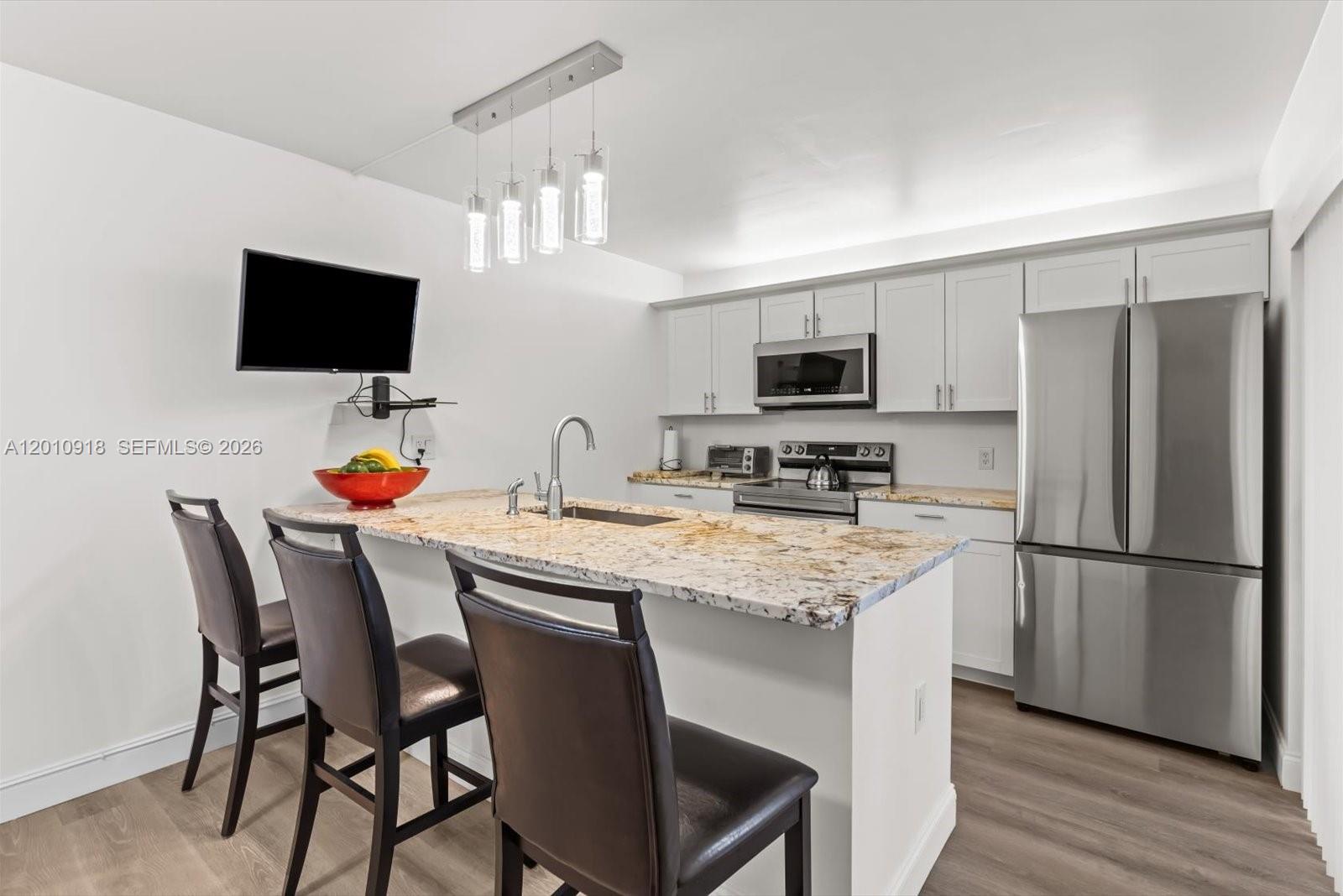 A kitchen features a granite-topped island, stainless steel appliances, and white cabinetry — 6001 60th Way, West Palm Beach FL 33409, WEST PALM BEACH, FL