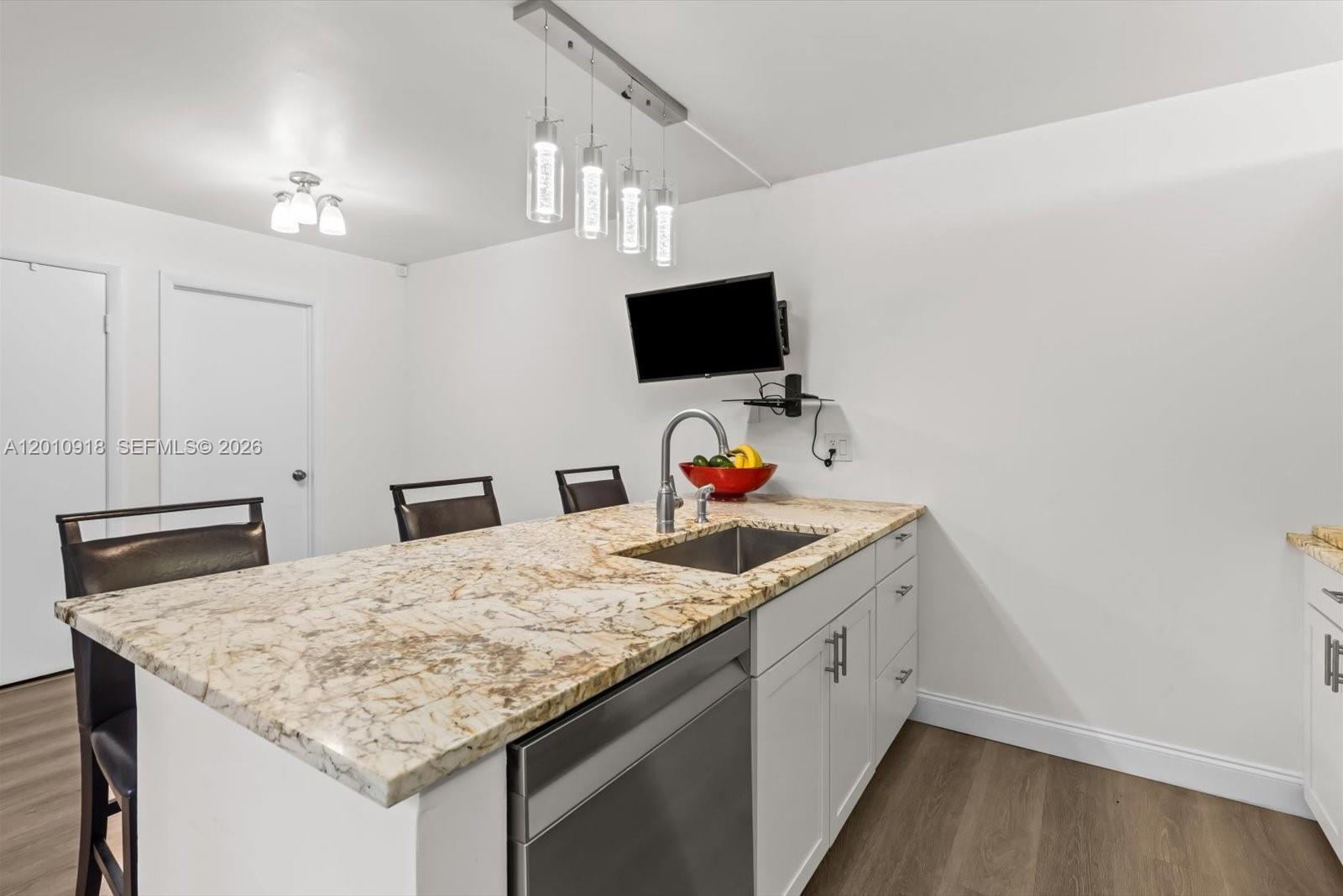 A kitchen island with a granite countertop, stainless steel sink, and pendant lighting — 6001 60th Way, West Palm Beach FL 33409, WEST PALM BEACH, FL