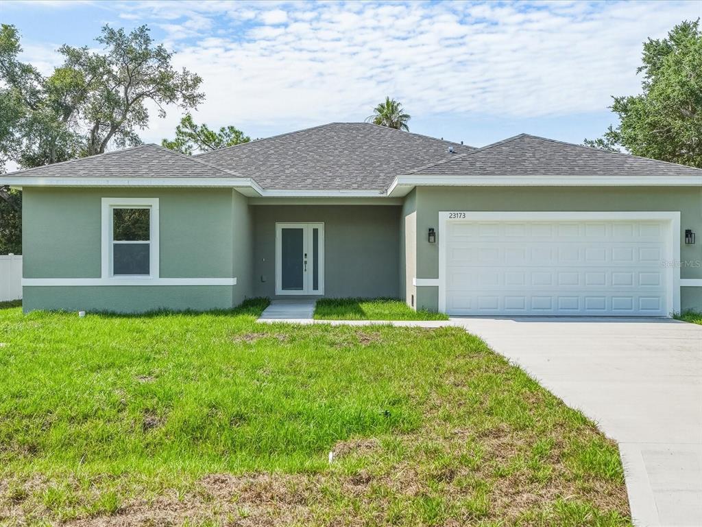 A single-story house with a green exterior, a gray shingled roof, and a two-car garage — 23173 GLEN AVENUE, PUNTA GORDA, FL