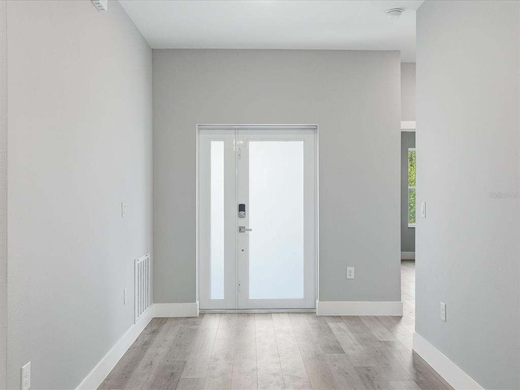 An entryway features light gray walls, wood-look flooring, and a white front door with sidelights — 23173 GLEN AVENUE, PUNTA GORDA, FL