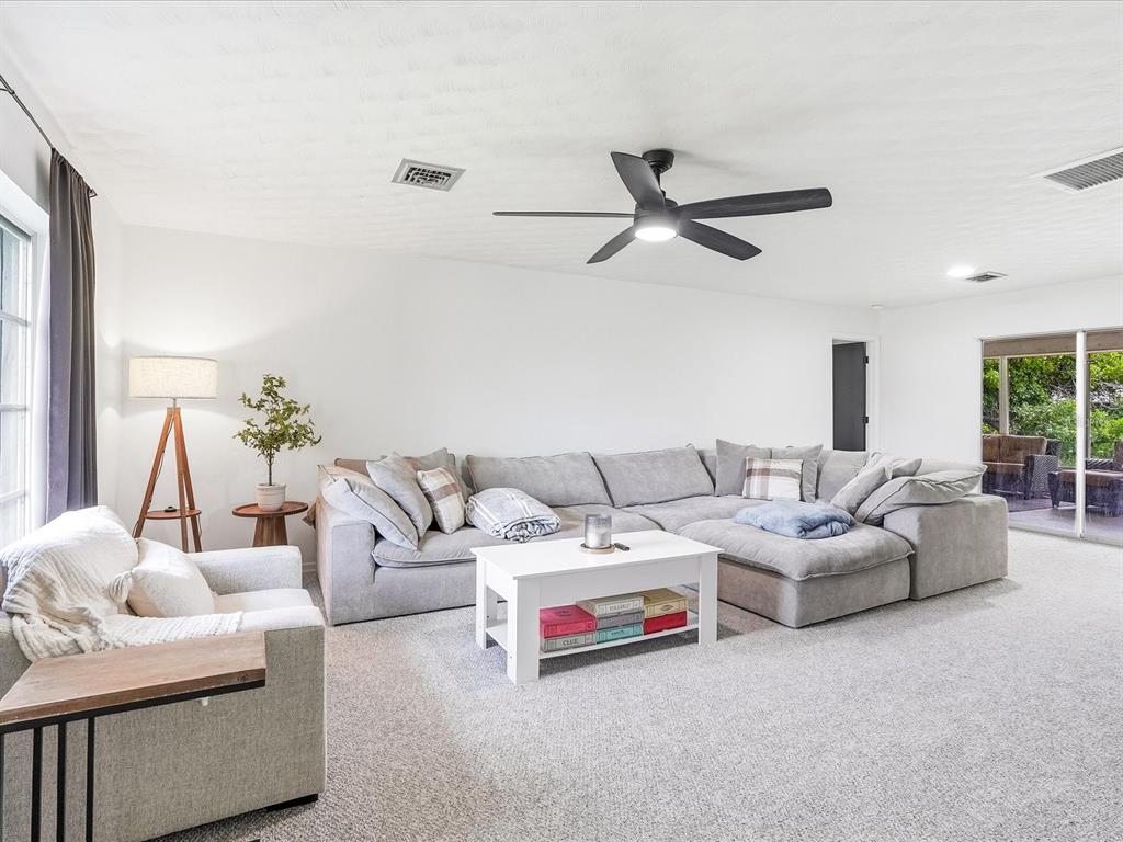 A living room with a large gray sectional sofa, white coffee table, and ceiling fan — 7238 SPINNAKER BOULEVARD, ENGLEWOOD, FL