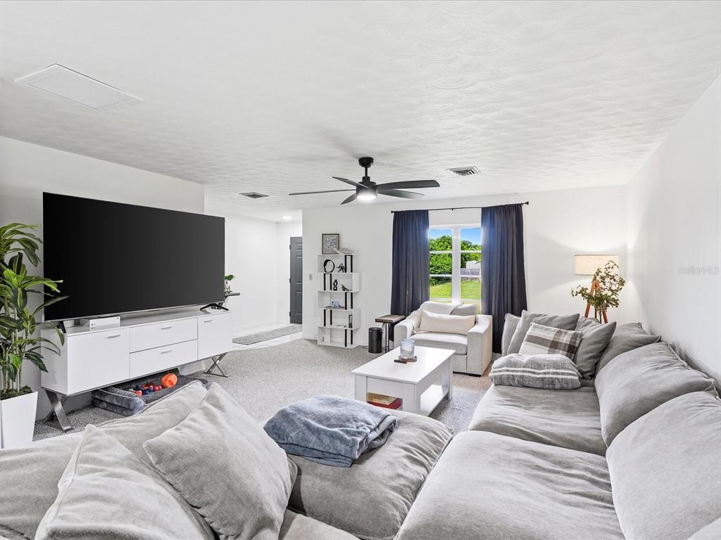 A living room features a large sectional sofa, a white media console, and a ceiling fan — 7238 SPINNAKER BOULEVARD, ENGLEWOOD, FL