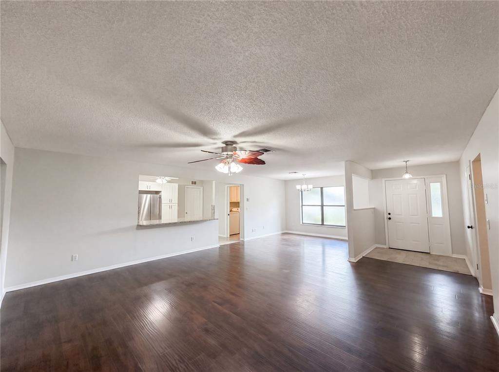An open-concept living area features dark wood flooring, a ceiling fan, and a kitchen pass-through — 10510 SW 74TH COURT, OCALA, FL