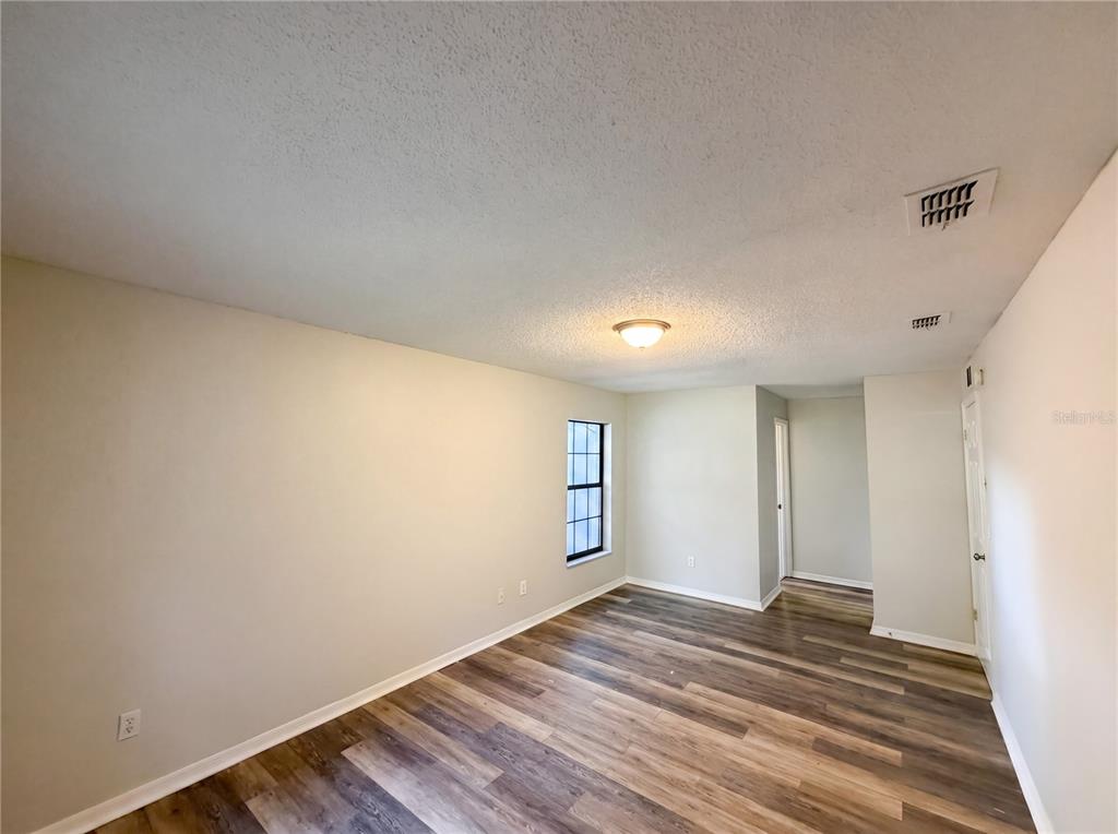 An empty room features light-colored walls, a single window, and wood-look vinyl plank flooring — 10510 SW 74TH COURT, OCALA, FL