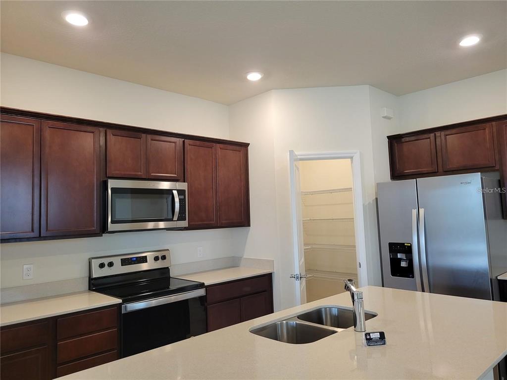 A kitchen features dark wood cabinets, stainless steel appliances, a kitchen island, and a pantry — 2713 FRANKLIN ROAD, ST CLOUD, FL