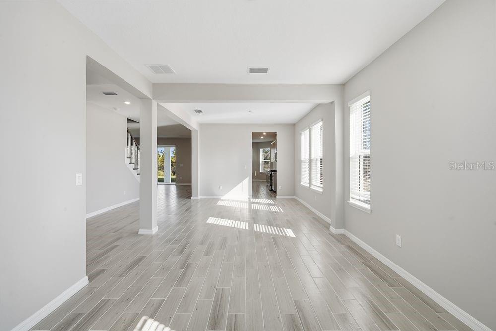 An empty room with light gray walls, wood-look tile flooring, and large windows — 1678 TRAILHEAD LANE, ZEPHYRHILLS, FL
