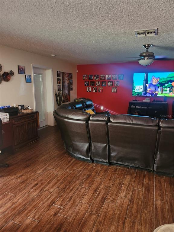 A living room features a large brown sectional sofa, wood-look tile floors, and a red wall — 2242 WOOD COURT, DELTONA, FL