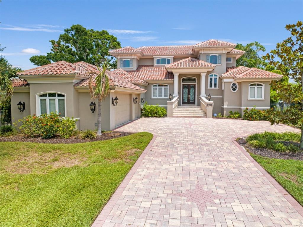 A two-story house with a tiled roof, beige stucco exterior, and a paved driveway — 5918 BAHAMA SHORES DRIVE S, ST PETERSBURG, FL