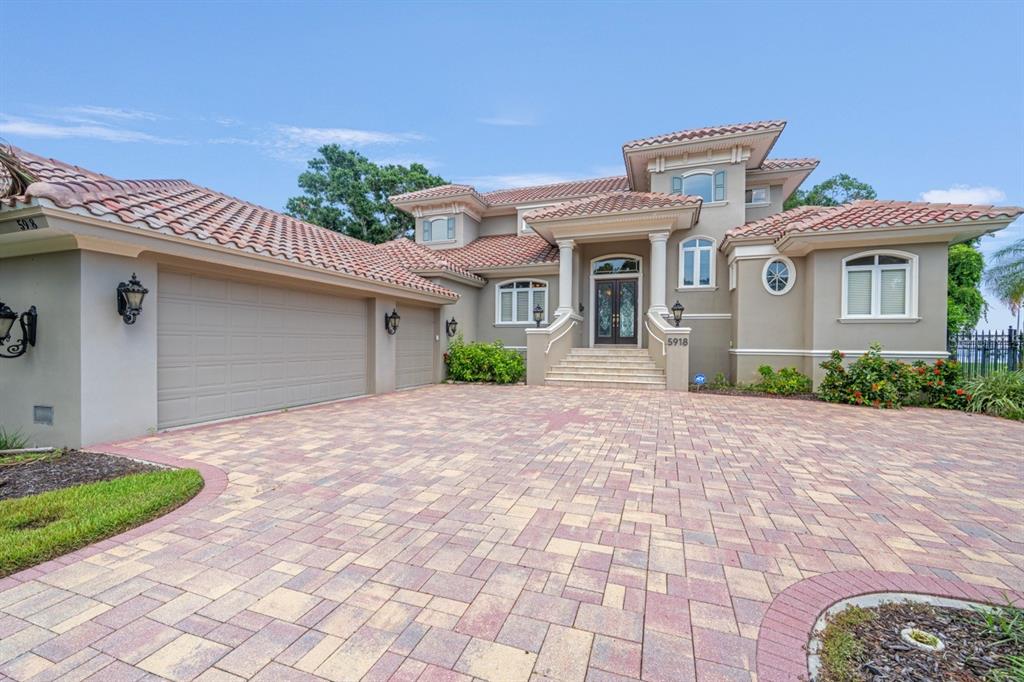 A two-story house with a tile roof, beige stucco exterior, and a paved driveway — 5918 BAHAMA SHORES DRIVE S, ST PETERSBURG, FL
