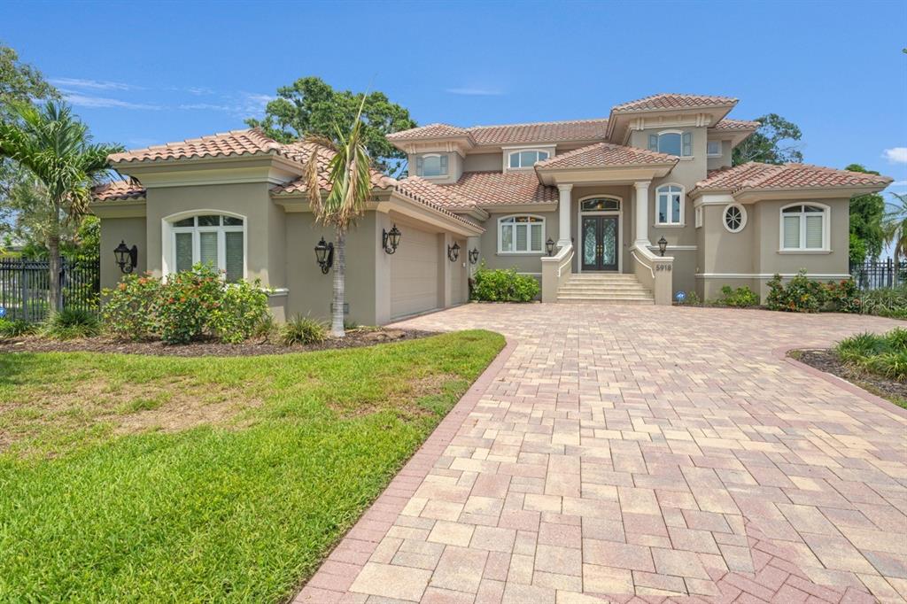 A two-story house with a tiled roof, beige stucco exterior, and a paved driveway — 5918 BAHAMA SHORES DRIVE S, ST PETERSBURG, FL
