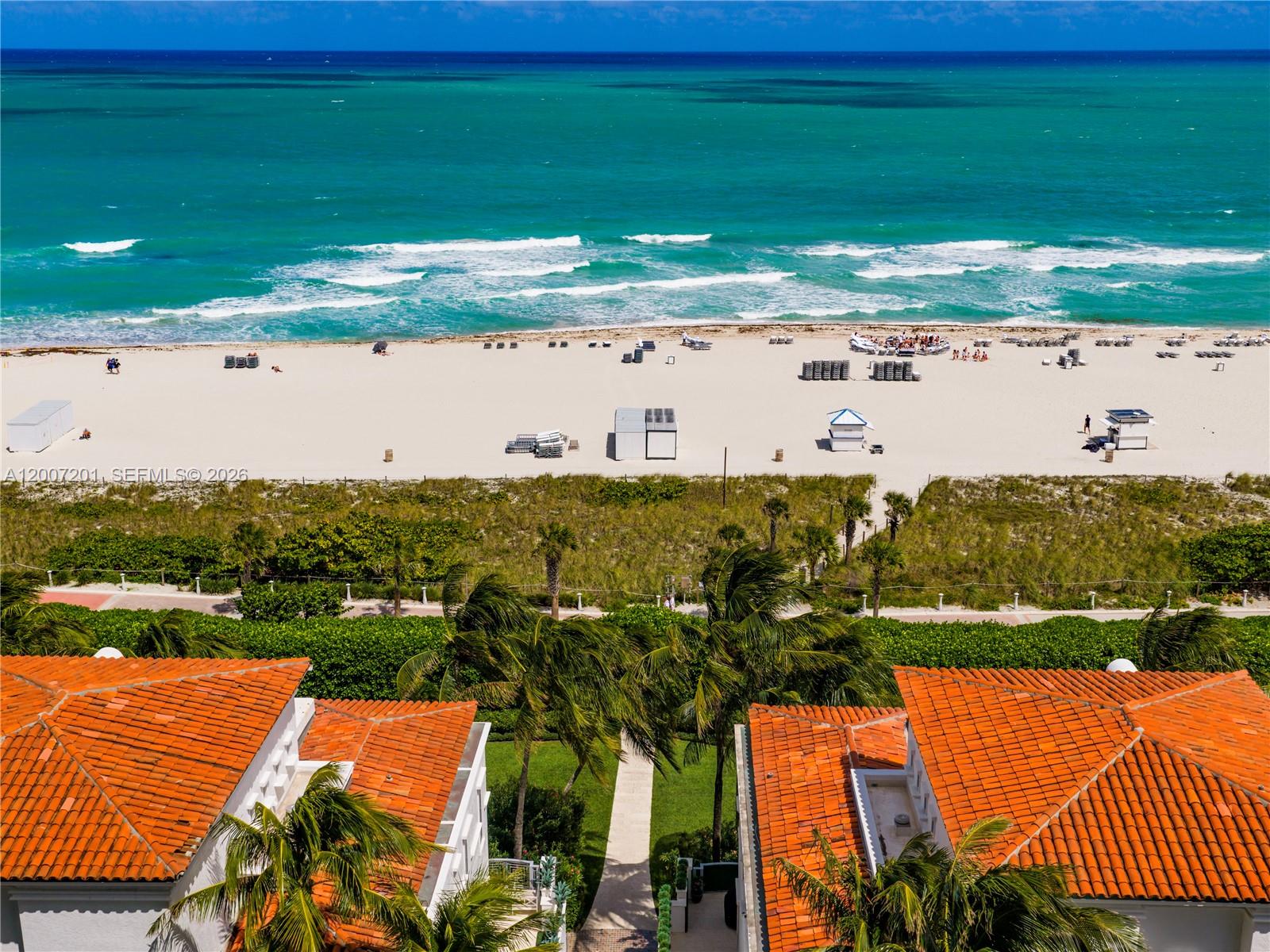 An aerial view shows a sandy beach, ocean, and two buildings with orange tile roofs — 5959 Collins Ave # 906, Miami Beach FL 33140, MIAMI BEACH, FL