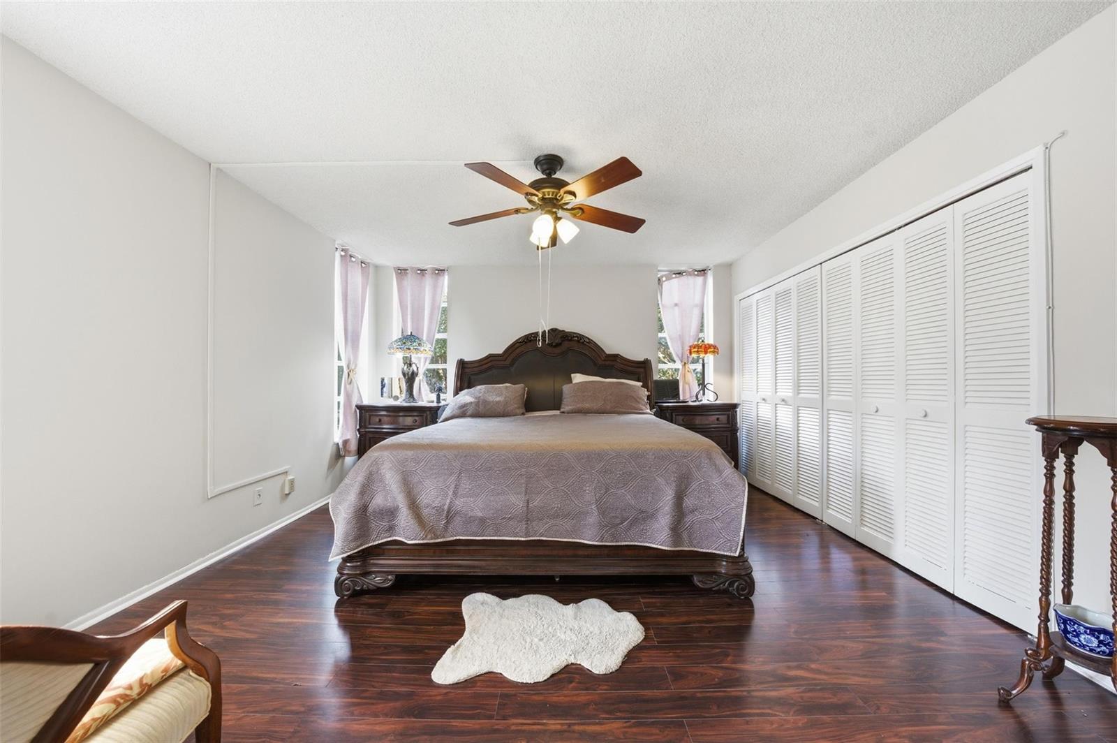 A bedroom features a dark wood bed frame, hardwood floors, and white louvered closet doors — 3000 S Course Drive # 201, Pompano Beach FL 33069, POMPANO BEACH, FL