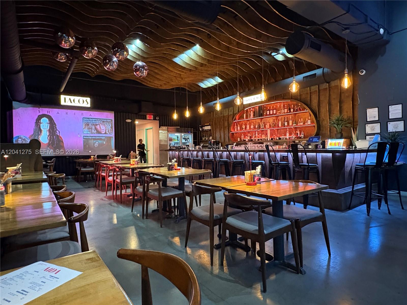 A restaurant interior features wooden tables, chairs, a bar, and a wavy wood-slat ceiling — 1111 SW 1, Miami FL 33130, MIAMI, FL