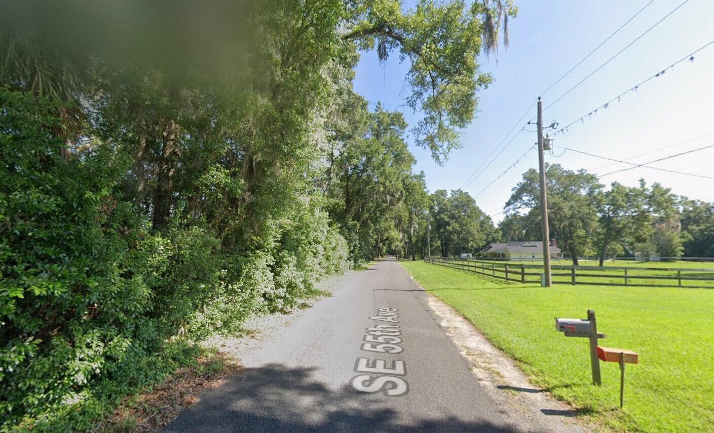 A narrow paved road runs between a wooded area and a grassy field with fencing — 1590 SE 55th Avenue, Ocala FL 34480, OCALA, FL
