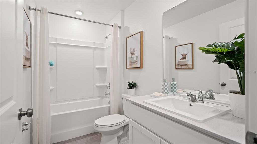 A bright bathroom features a white vanity, a toilet, and a shower-tub combination — 2263 JENNIO DRIVE, HAINES CITY, FL