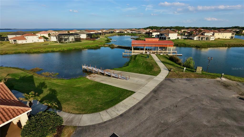 An aerial view shows a community lake with a boat dock and a covered pavilion — 3311 BENT PADDLE DRIVE, KISSIMMEE, FL