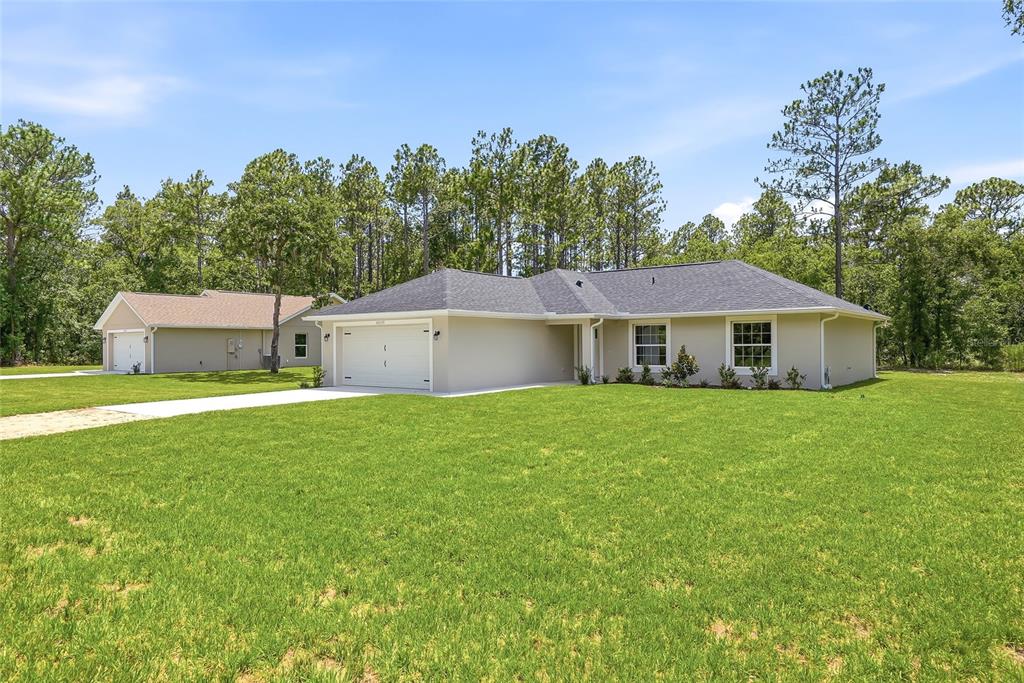 A single-story house with a two-car garage and a detached garage on a grassy lot — 16335 FORCE ROAD, WEEKI WACHEE, FL