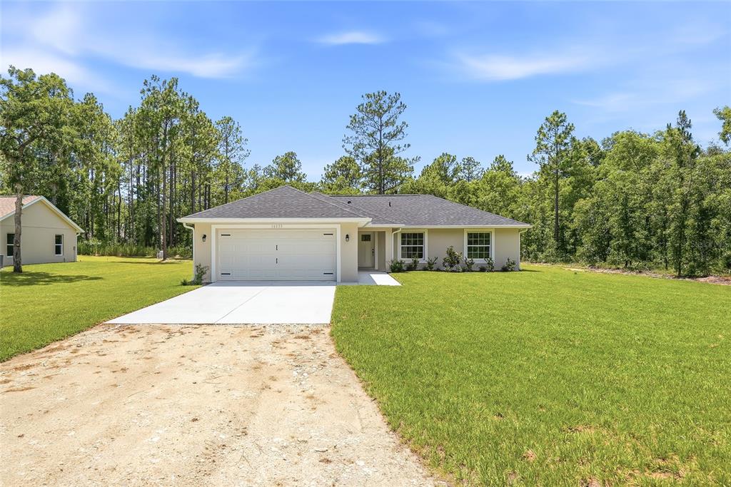 A single-story house with a white garage, beige exterior, and a concrete driveway — 16335 FORCE ROAD, WEEKI WACHEE, FL