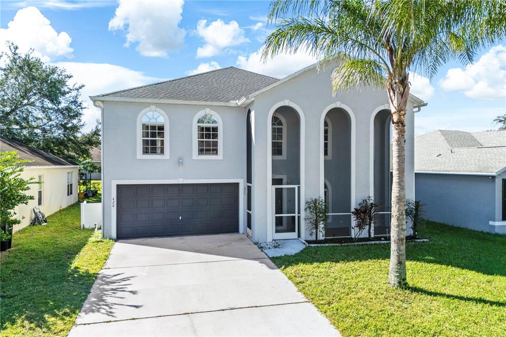 A two-story house with a gray exterior, a two-car garage, and arched entryway features — 420 BLAKE AVENUE, DAVENPORT, FL