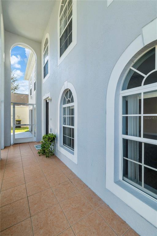 A covered outdoor patio with light blue walls, arched windows, and tiled flooring — 420 BLAKE AVENUE, DAVENPORT, FL