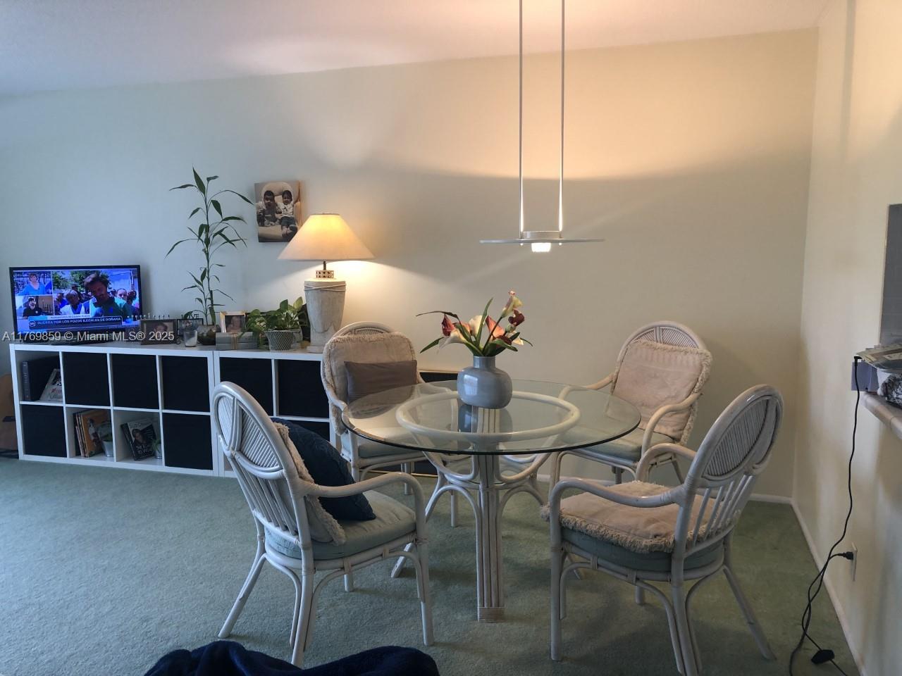 A dining area features a glass-topped table with four wicker chairs on green carpet — 1000 NE 14th Ave # 605, Hallandale Beach FL 33009, HALLANDALE BEACH, FL