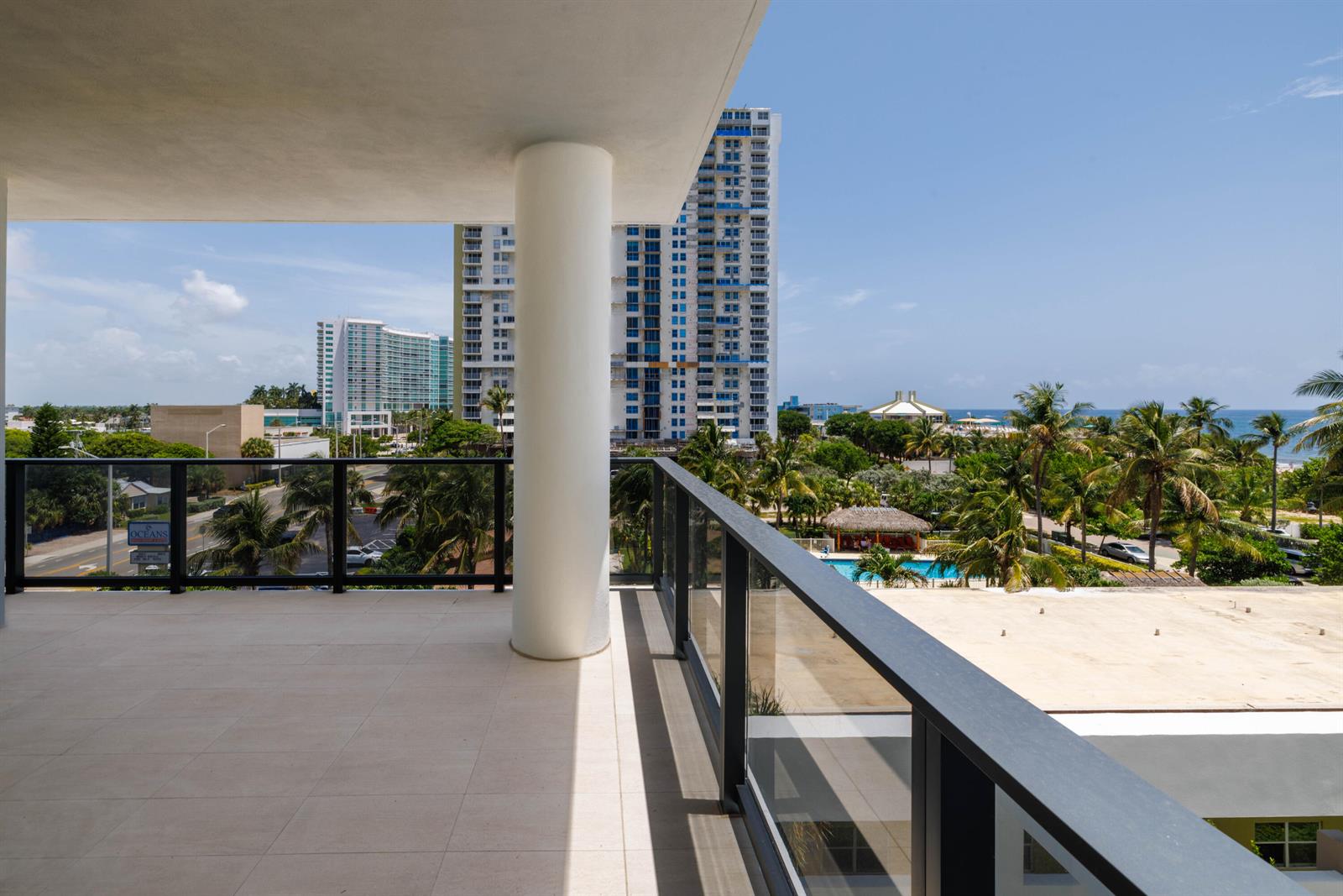 A spacious balcony with tile flooring, a white support column, and a glass railing — 305 Briny Avenue # 406, Pompano Beach FL 33062, POMPANO BEACH, FL