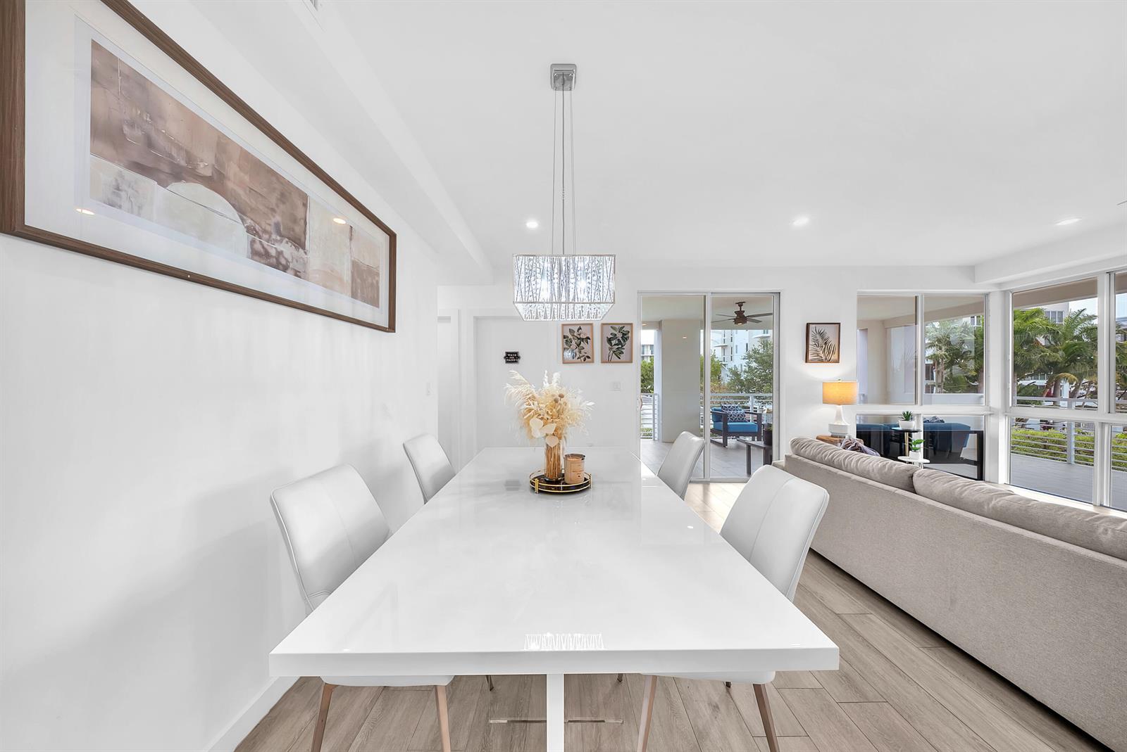 A dining area with a white table and chairs sits adjacent to a living room — 51 SE 19th Avenue # 303, Deerfield Beach FL 33441, DEERFIELD BEACH, FL