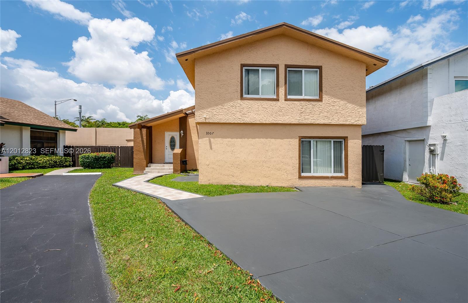 A two-story, tan stucco house features a paved walkway leading to the front entrance — 1007 NW 106th Ave Cir, Miami FL 33172, MIAMI, FL