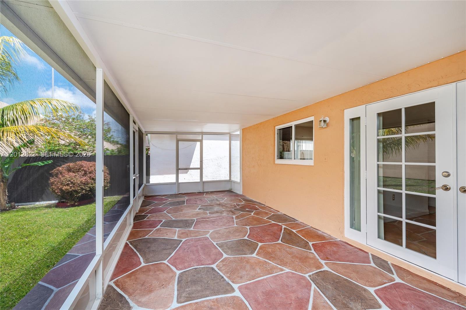 A screened-in patio features a multi-colored stone floor and a light orange exterior wall — 1007 NW 106th Ave Cir, Miami FL 33172, MIAMI, FL