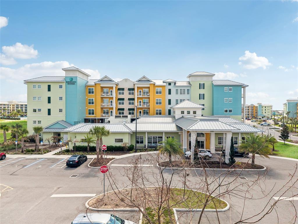 A multi-story Embassy Suites hotel building features a colorful facade and a large parking lot — 3151 SUNSET WALK DRIVE UNIT 1209, KISSIMMEE, FL