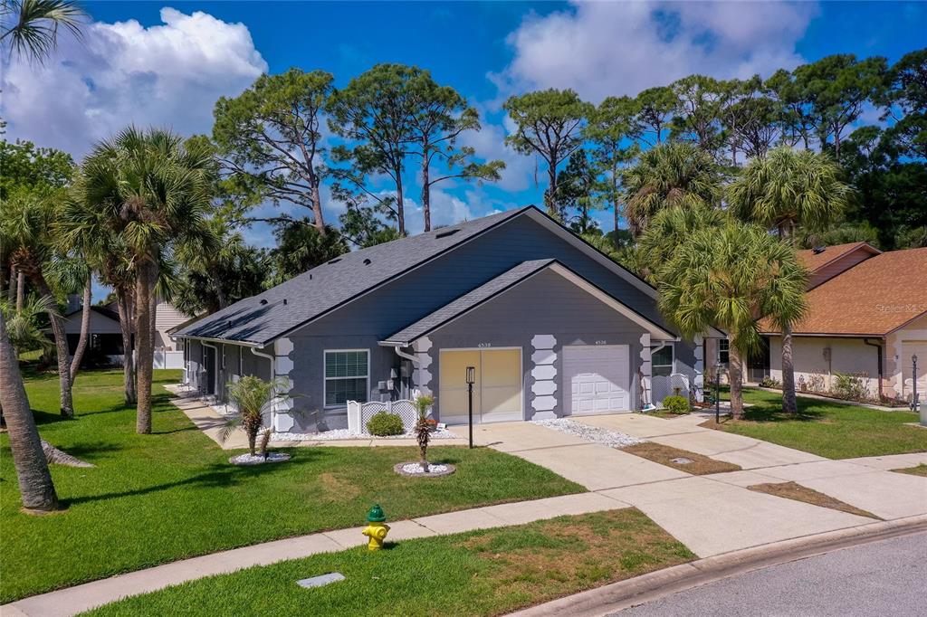 A gray duplex with two garage doors and white trim sits on a grassy lot — 4538 ROCKLEDGE LANE, PORT ORANGE, FL