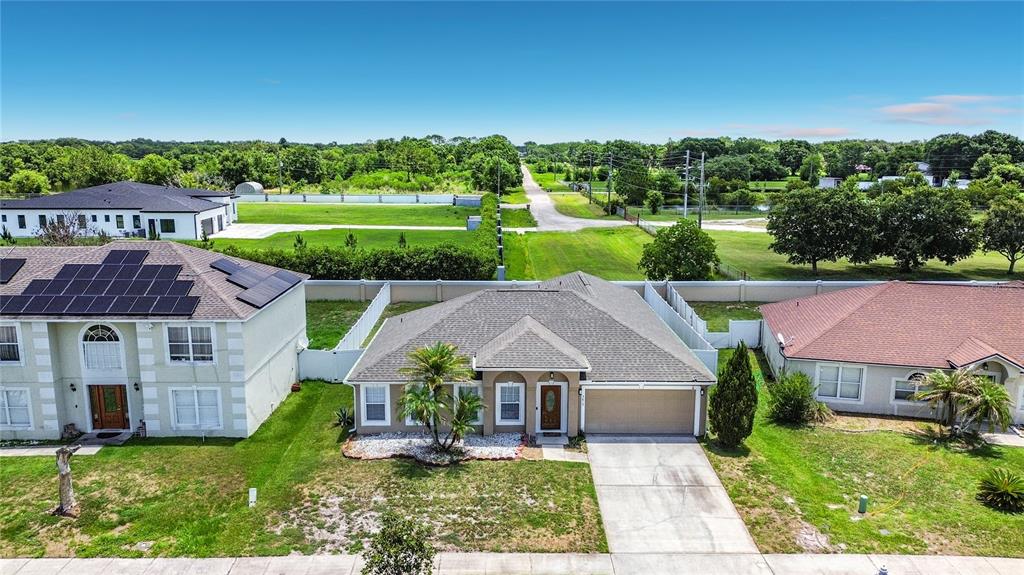 An aerial view shows a single-story suburban house with a tan exterior and gray roof — 3013 MANDOLIN DRIVE, KISSIMMEE, FL