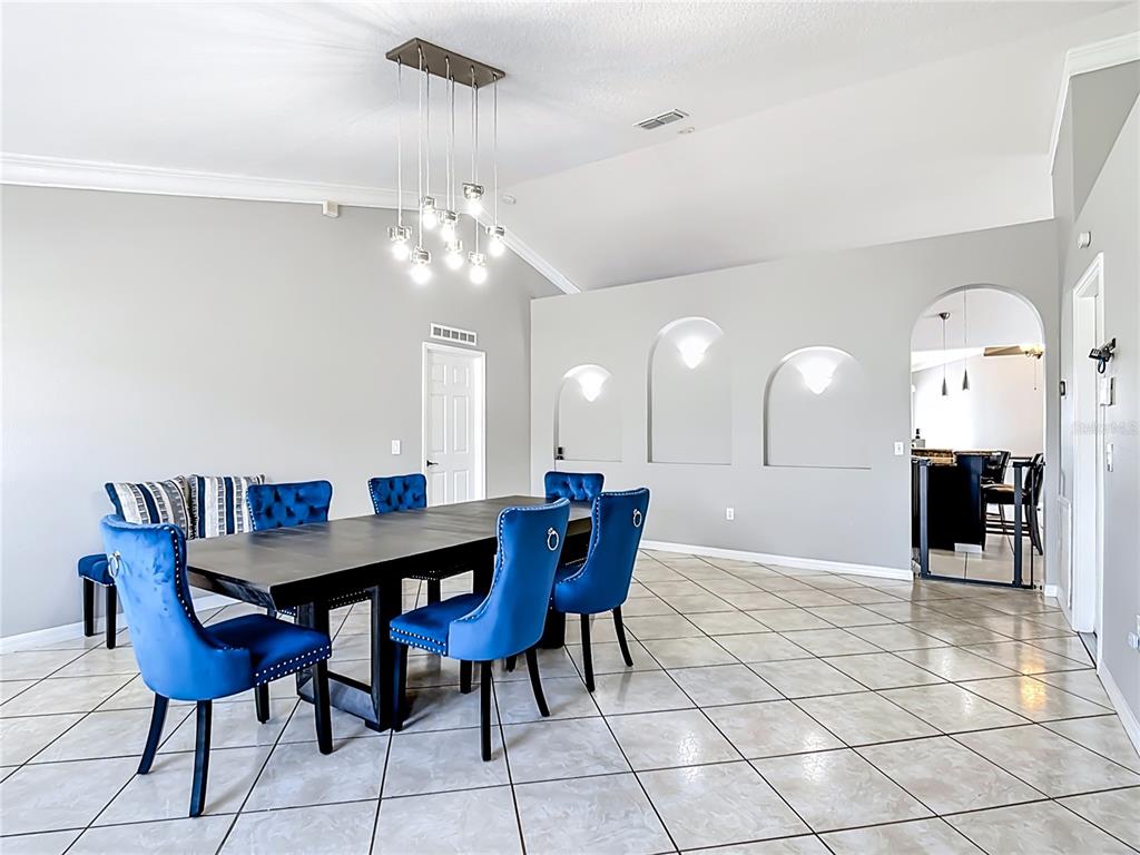 A dining room features a dark table, blue velvet chairs, and three arched wall niches — 3013 MANDOLIN DRIVE, KISSIMMEE, FL