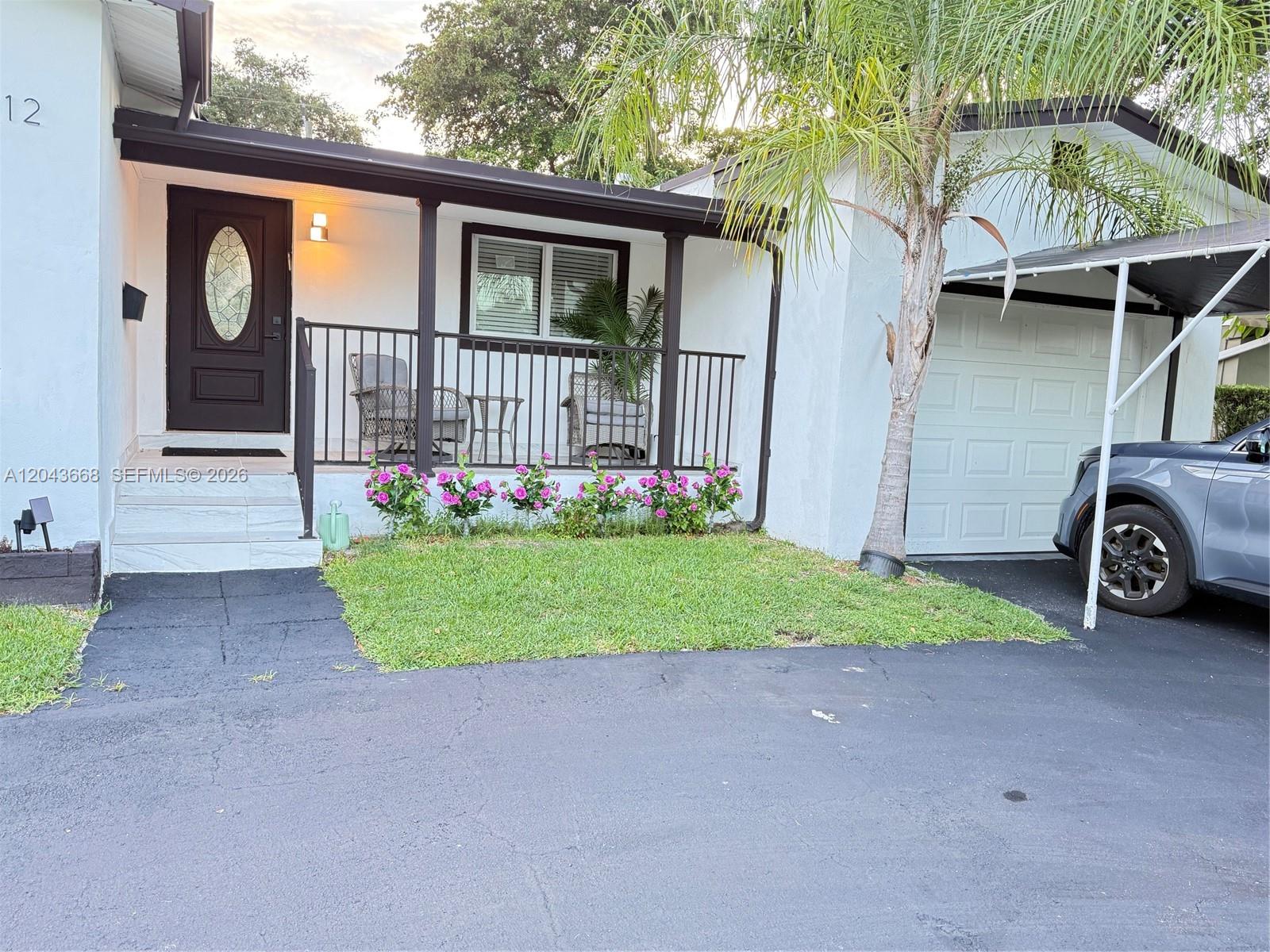 A white house features a covered front porch, a black metal railing, and a driveway — 1912 N 42nd Ave, Hollywood FL 33021, HOLLYWOOD, FL