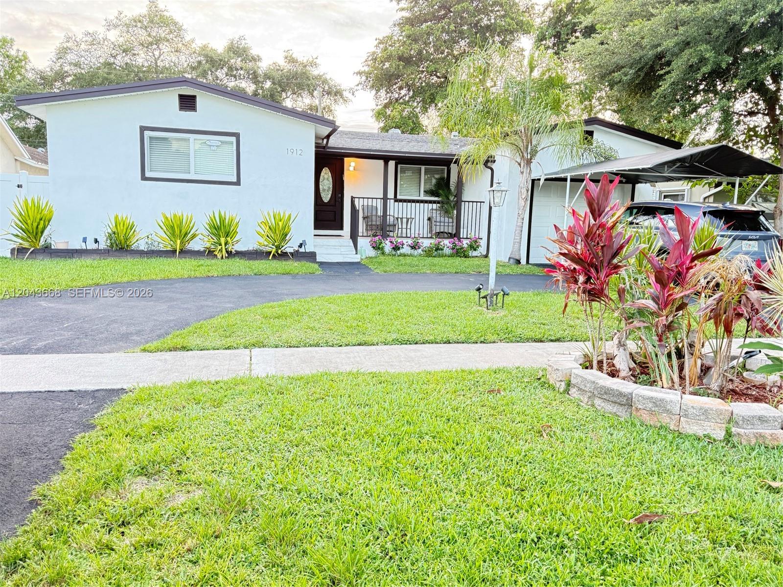 A single-story house with a white exterior, dark trim, a front porch, and a carport — 1912 N 42nd Ave, Hollywood FL 33021, HOLLYWOOD, FL