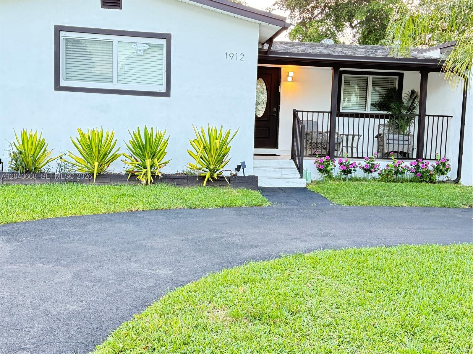 The exterior of a white house features a front porch, a driveway, and landscaping — 1912 N 42nd Ave, Hollywood FL 33021, HOLLYWOOD, FL