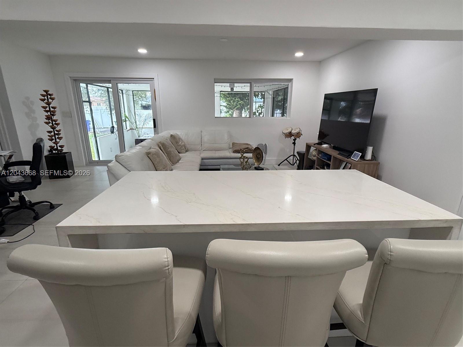 A kitchen island with a white countertop sits in front of a living room area — 1912 N 42nd Ave, Hollywood FL 33021, HOLLYWOOD, FL