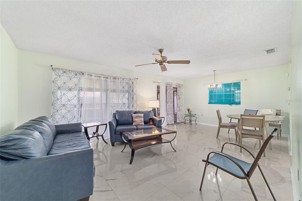 A living and dining area with blue sofas, a coffee table, and light tile flooring — 15083 SW 43RD TERRACE ROAD, OCALA, FL