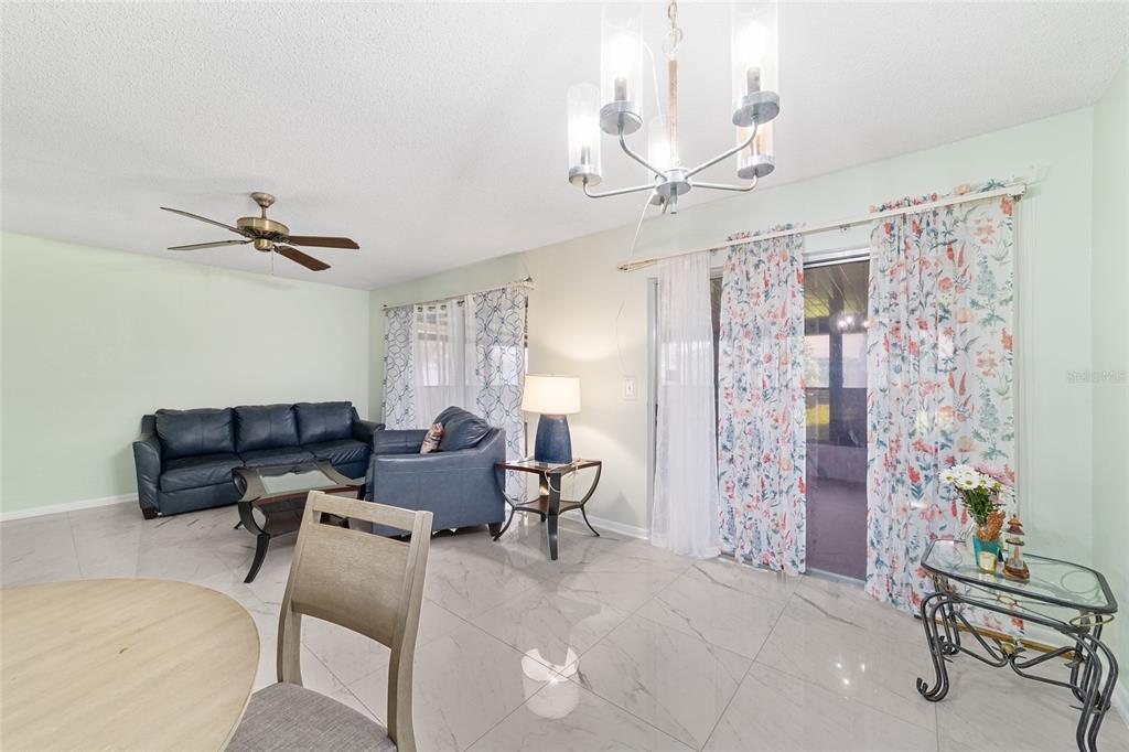 A living and dining area features light-colored tile flooring, a ceiling fan, and floral curtains — 15083 SW 43RD TERRACE ROAD, OCALA, FL