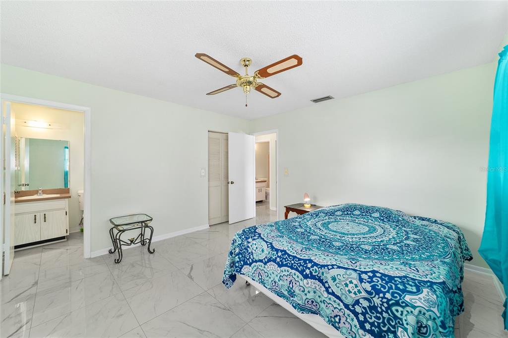 A bedroom with white tile floors, a ceiling fan, and a bed with blue bedding — 15083 SW 43RD TERRACE ROAD, OCALA, FL