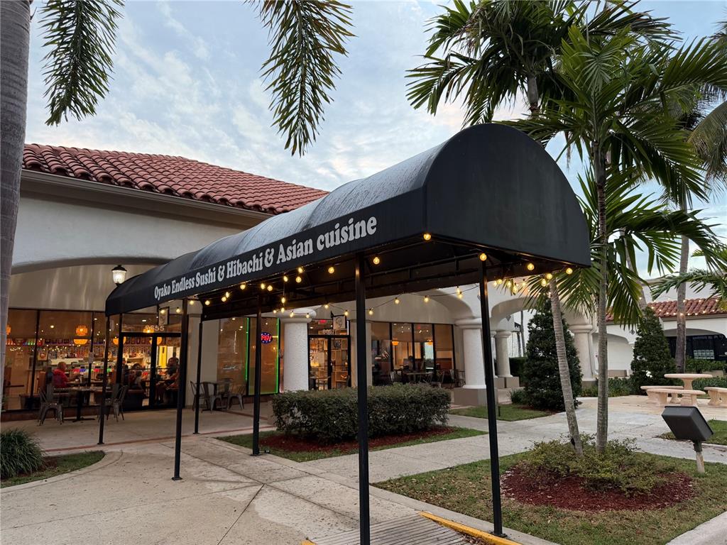 The exterior of a restaurant features a black awning with string lights and palm trees — TBA BOYNTON BEACH BOULEVARD, BOYNTON BEACH, FL