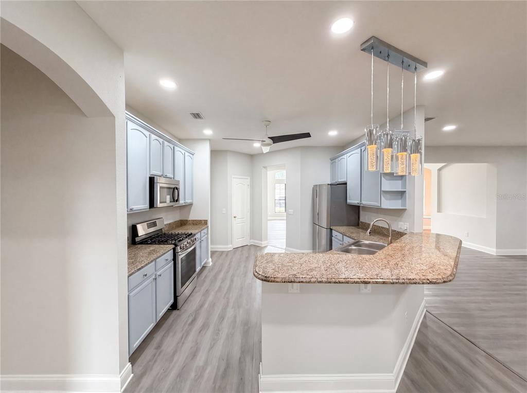 A kitchen features light blue cabinets, granite countertops, stainless steel appliances, and a breakfast bar — 216 BLUE CRYSTAL DRIVE, DELAND, FL
